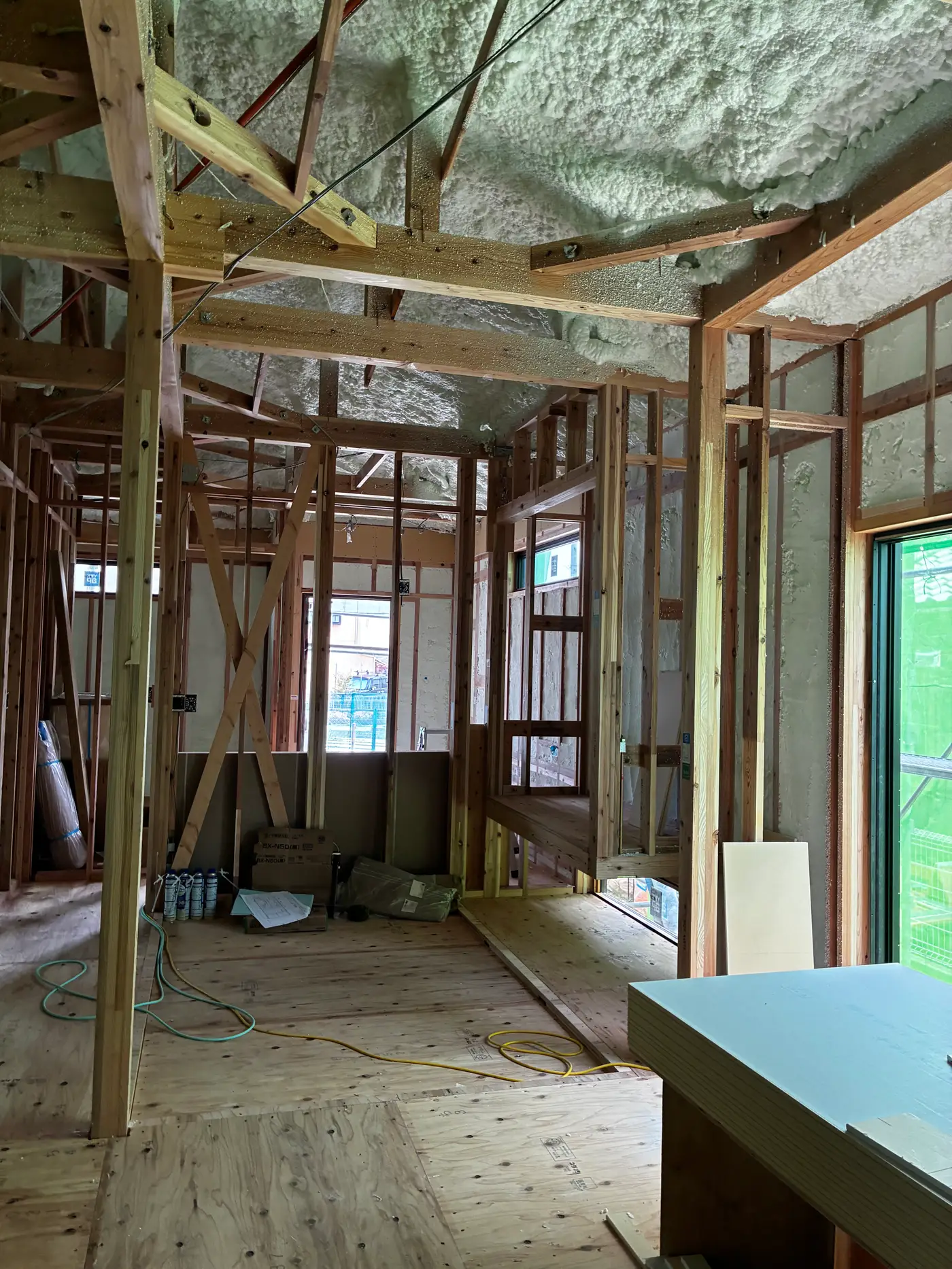 Interior partition wall framing in a Japanese house, showing bare uninsulated studs with electrical outlet and switch boxes mounted on them