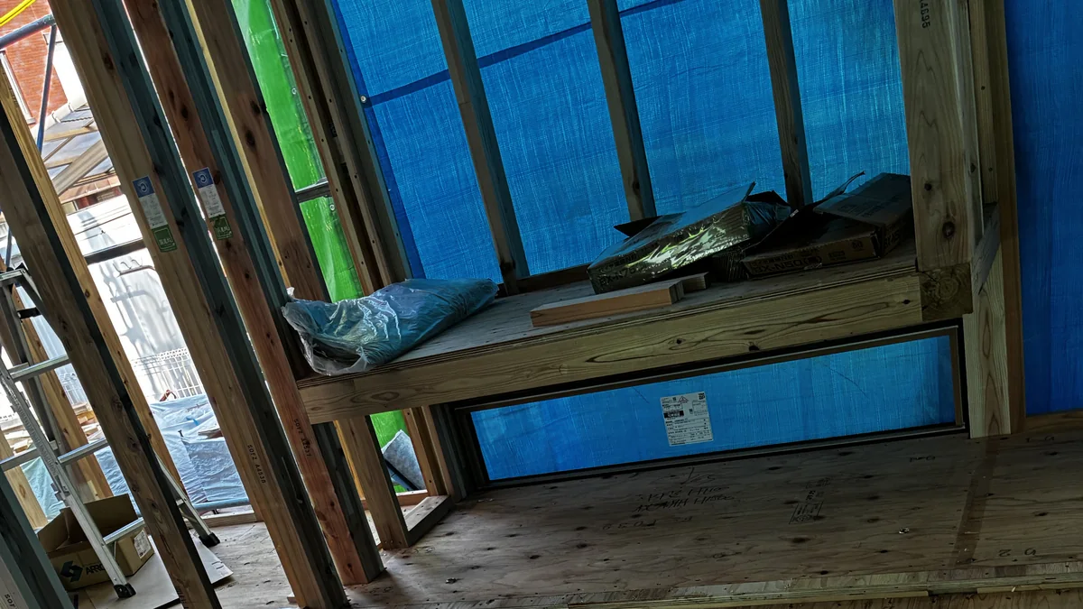 Interior wall of a Japanese house under construction, sheathed in structural plywood with a window opening framed in timber