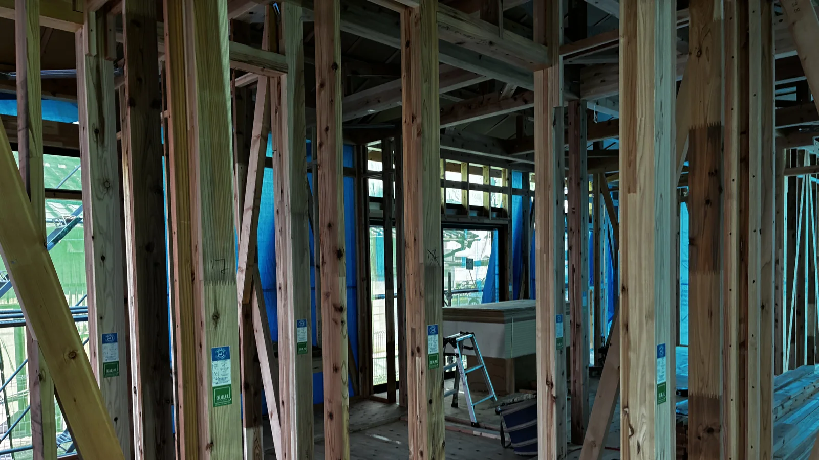 The interior timber frame of a Japanese house under construction, showing square posts, diagonal bracing, and structural plywood sheathing before the walls are closed