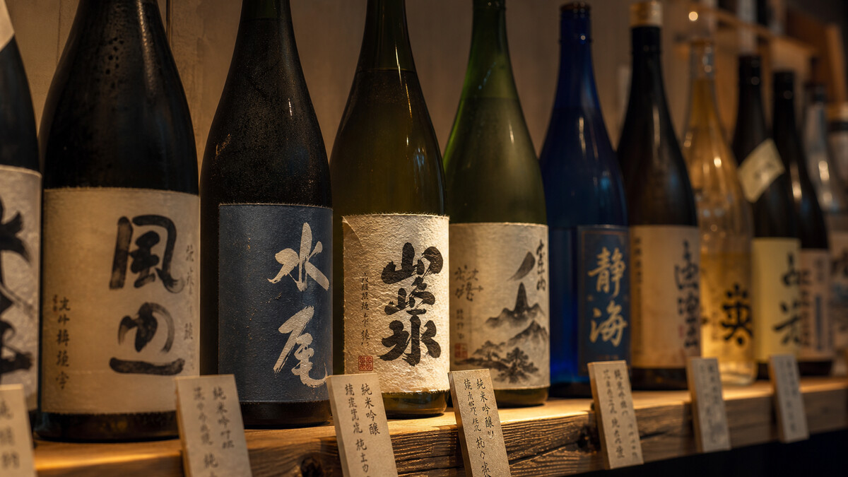 A row of sake bottles with Japanese labels on a shop shelf